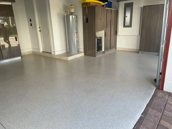 Light gray flake epoxy garage floor with wood cabinets in Fort Lauderdale, FL